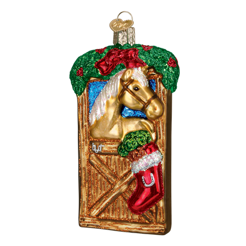 Decorative Christmas ornament with a horse in a stable, with a red stacking hanging on the stall. 