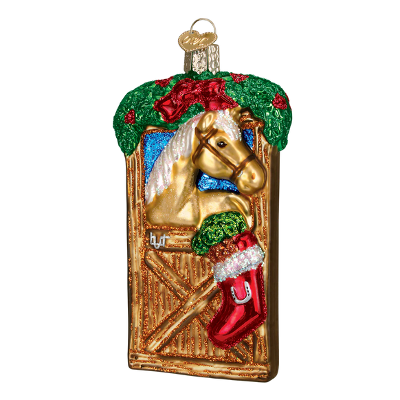 Decorative Christmas ornament with a horse in a stable, with a red stacking hanging on the stall. 