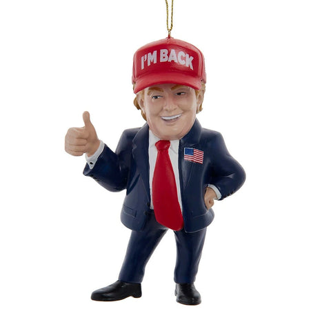 Novelty political ornament featuring a suited figure in a red “I’m Back” hat, red tie, and patriotic lapel pin giving a thumbs-up.