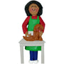 Ornament of a woman with a green apron grooming a dog on a white table.