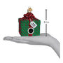 Christmas ornament shaped like a gift box with a gift tag that say "Junk in the Box" on a hand for scale, showing a height of 3.5 inches.