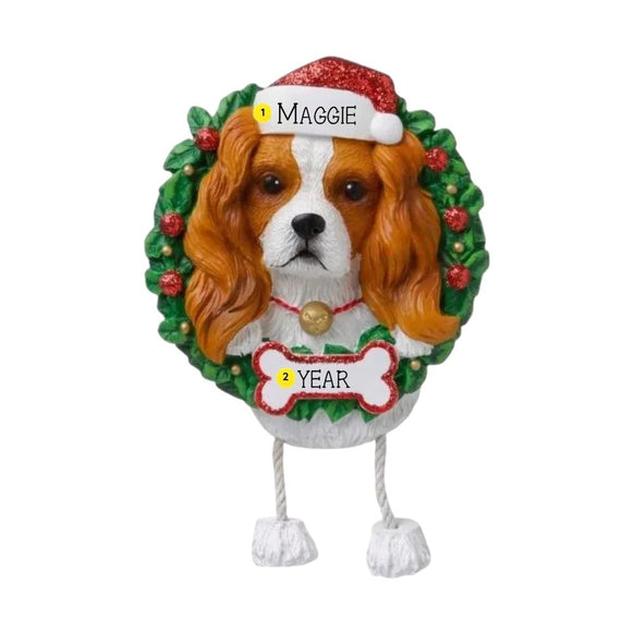 Personalized Cavalier King Charles Spaniel ornament with a brown and white dog in a Santa hat framed by a green wreath with space for a name and year.