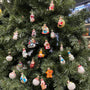 Assorted mini glass Christmas ornaments from the advent calendar displayed on the branches of a tabletop tree.