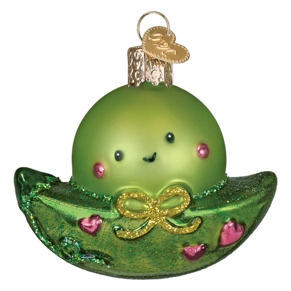 Green glass ornament shaped like a peapod with a face on a white background