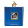 Blue book-shaped ornament with a small illustration of a bear peeking out from under a blanket, on a white background.