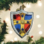 Decorative Christmas ornament shaped like a shield with red, blue, and yellow colors, hanging on a tree.