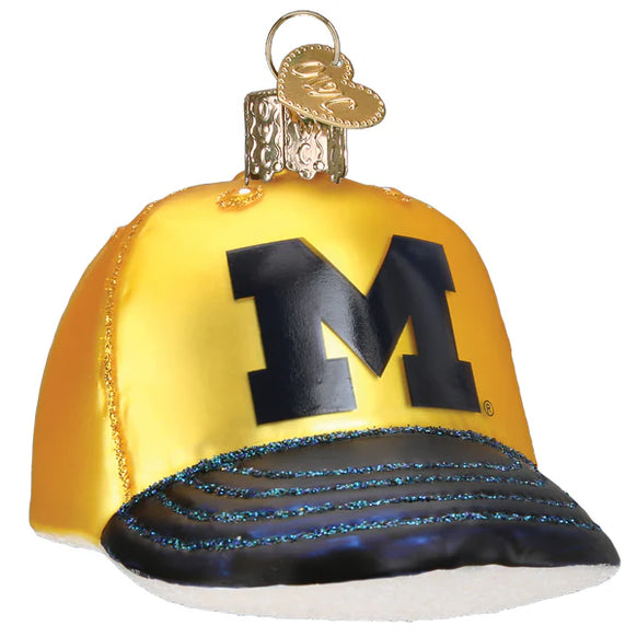 Glass ornament of a yellow baseball cap with a black 'M' for Michigan on a white background
