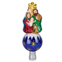 Nativity tree topper featuring Mary, Joseph, and Baby Jesus beneath a gold star on a blue ornament-style base with snowy white accents.