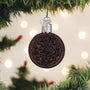 Decorative ornament shaped like an Oreo cookie on a Christmas tree with lights in the background
