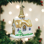 Golden Cathedral Ornament by Old World Christmas hanging on a Christmas tree with warm lights in the background.