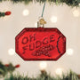 Red 'Oh Fudge' Christmas ornament on a tree with lights in the background