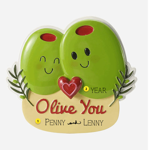 Two green olives with faces and a heart, labeled 'Olive You' ornament, on a beige base with text.