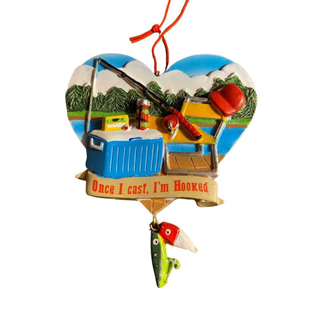 Fishing-themed ornament featuring camping and tackle details, evergreen trees, and the phrase “Once I cast, I’m Hooked.”