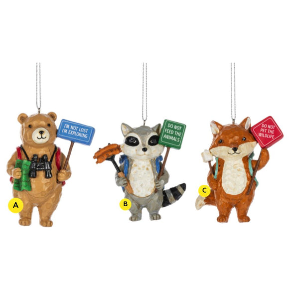 Three whimsical Outdoor Forest Animal PSA ornaments shown together, featuring a bear with binoculars and an “I’m Not Lost I’m Exploring” sign, a raccoon roasting food with a “Do Not Feed the Animals” sign, and a fox holding a marshmallow stick with a “Do Not Pet the Wildlife” sign.