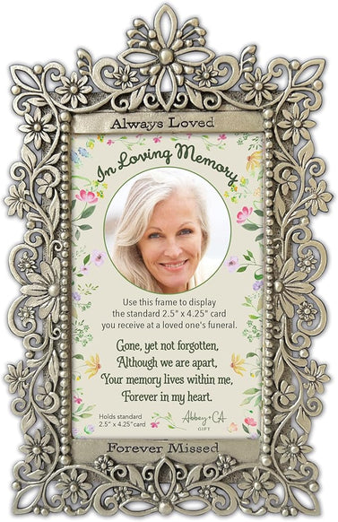 Decorative silver-tone floral memorial card frame with intricate scrollwork, designed to hold a standard funeral memorial card.