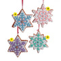 Four pastel cookie ornaments in star and snowflake shapes with white icing and blue, pink, purple, and mint decorative details.
