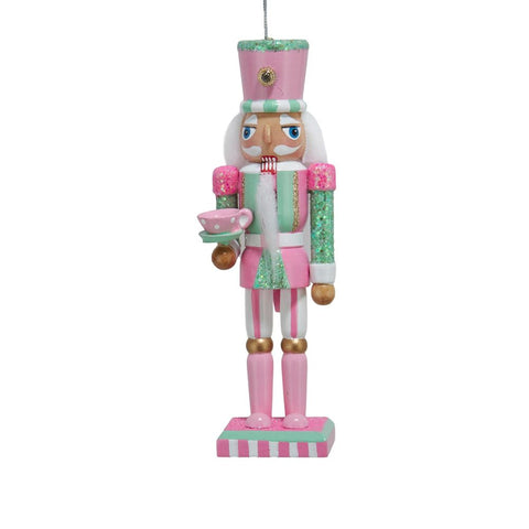 Pink and mint nutcracker ornament with glittered accents, tall hat, white beard, and pink teacup with saucer on a striped base.
