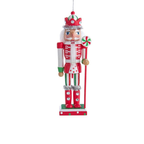 Red, white, and green nutcracker ornament with a jeweled crown, white beard, silver tinsel trim, and peppermint lollipop staff on a rectangular base.