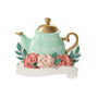 A Baby is Brewing expecting ornament with a mint teapot, gold lid and handle, pink flowers, greenery, and a white banner.