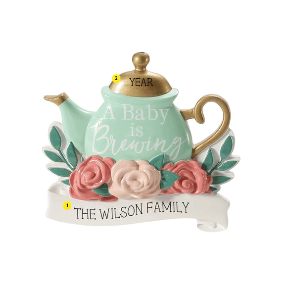 Personalized A Baby is Brewing expecting ornament with a family name on the white banner and year on the gold teapot lid.