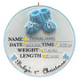 Decorative ornament with blue baby booties and newborn details on a white background