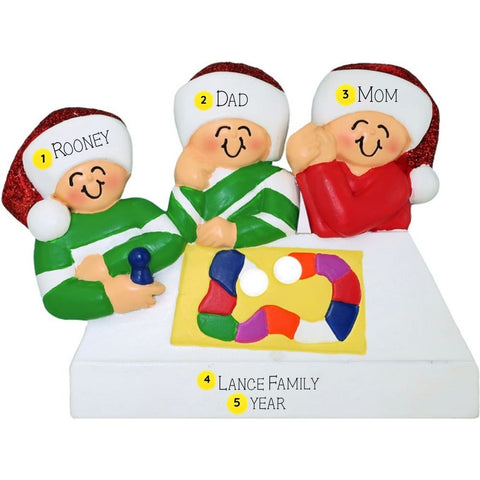 Personalized Christmas ornament of a family with children holding playing a board game, on a white background.