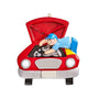 This detailed ornament features a mechanic leaning over the open hood of a classic red car while working on the engine. 