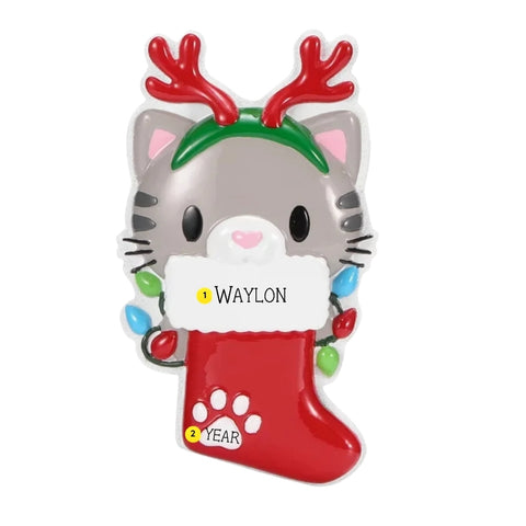 Personalized cat with reindeer antlers ornament with a pet name written on the stocking cuff and the year added near the paw print.