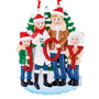 JOY family of 4 ornament with two parents and two children in winter clothes holding red glitter letters in front of snowy evergreen trees.