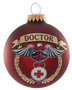 A round red Christmas ornament featuring a medical theme with a gold banner reading 'DOCTOR', a caduceus symbol, a white medical cross, and a gold laurel wreath, shown on a plain white background.
