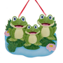 Frog pond family of three ornament with three smiling frogs, lily pads, reeds, and pink water lilies.