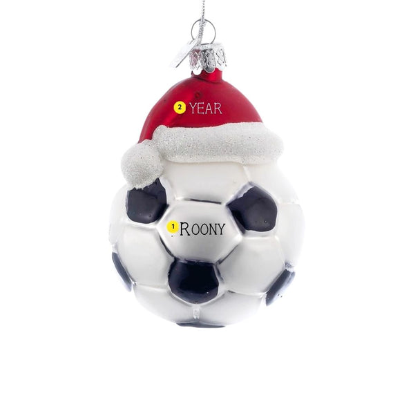 Personalized glass soccer ball ornament with black and white panels, red Santa hat, glittery white trim, silver cap, and hanging cord.
