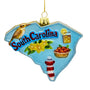 Front view of Personalized Glass South Carolina Ornament with state shape, South Carolina lettering, bird, yellow jasmine flowers, tea, peach pie, lighthouse, and blue glitter trim.