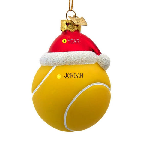 Personalized glass tennis ball ornament with red Santa hat, white glitter trim, gold cap, and name and year personalization guide.