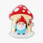 Gnome ornament with a red hat and blue coat, standing in front of a red and white spotted mushroom house with a small mailbox.