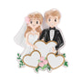 Happy wedding couple ornament with bride, groom, three gold-trimmed hearts, pink flowers, and glittery white accents.