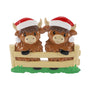 Highland cow couple ornament with two cows in Santa hats standing behind a fence.