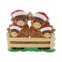 Highland cow family ornament with four cows in Santa hats standing behind a fence.