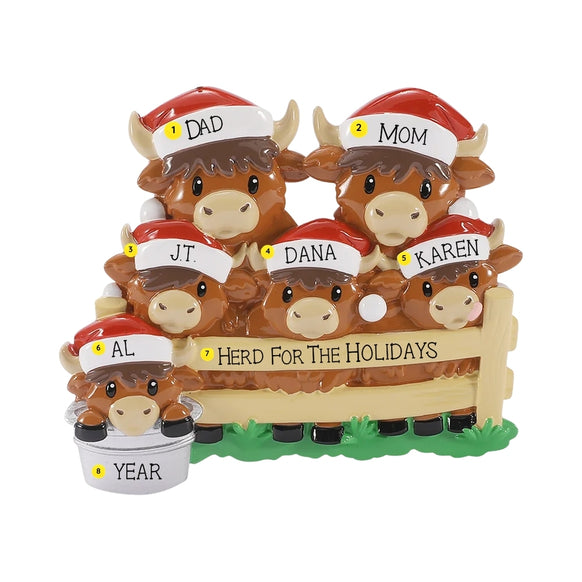 Personalized Highland cow family ornament with names on the Santa hats, a holiday phrase on the fence, and year on one bucket.