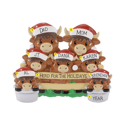 Personalized Highland cow family ornament with names on the Santa hats, a holiday phrase on the fence, and year on one bucket.