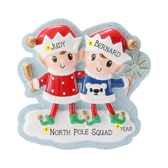 Two Christmas elves ornament personalized with two names on the hats, a short phrase on the snowy base, and a year.