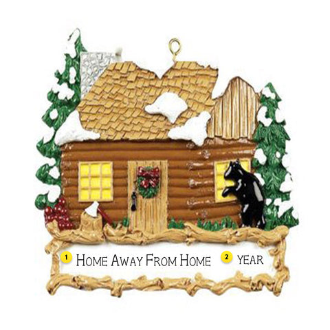 Decorative ornament of a log cabin with a bear and trees