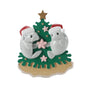 Manatee couple ornament with two manatees in Santa hats beside a coastal Christmas tree with starfish accents.
