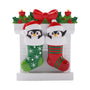 Penguin couple ornament in green and red Christmas stockings with Santa hats, holly, candles, and bow.