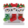 Penguin family of three ornament with red and green Christmas stockings, Santa hats, holly, and candles.