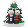 Christmas ornament with two people in sweaters and hats in front of a Christmas tree.