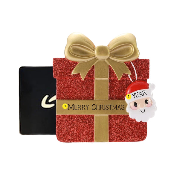 Personalized red glitter gift box money holder ornament with a Christmas phrase on the gold ribbon and year on Santa’s hat.