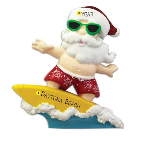 Personalized surfing Santa Christmas ornament with Santa in green sunglasses riding a yellow surfboard, shown with Daytona Beach and a year example.