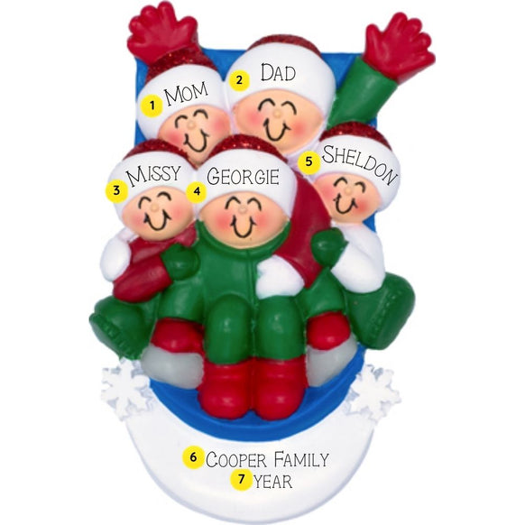 Personalized ornament of five smiling figures riding a blue sled through snow in matching winter clothes.