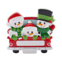 Snowman family of three ornament riding in a red holiday truck with festive winter accessories.